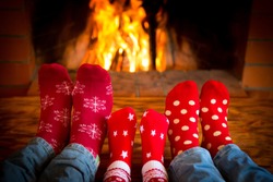 Family relaxing at home. Feet in Christmas socks near fireplace. Winter holiday concept