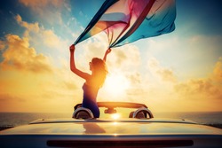 Silhouette of beautiful woman relaxing on the beach. Person having fun in cabriolet against blue sky background. Summer vacation and travel concept