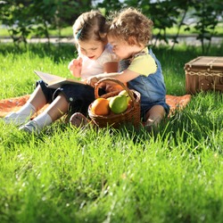 Children reading the book on picnic in summer park