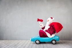 Santa Claus riding toy car. Senior man speaking into megaphone. Christmas Xmas holiday concept