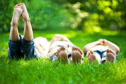 Group of happy children lying on green grass outdoors in spring park