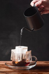 Soft Drink : a mug of coffee / a hand with black dripping pot pouring boiled hot water to coffee dripper on wooden table and black background at home with copy space
