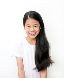 Portrait of beautiful young Asian teenage girl with long wavy black hair on white background. Pre teen girl in white t-shirt with Healthy black Hair smiling. Health And Beauty Concept.