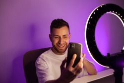 Smiling Men in shoots a photo and video on a phone with a ring lamp, portrait