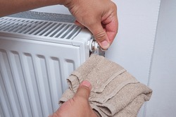 Hands with a kitchen towel and key for draining air drains water and air from the heater. Bleed air valve in heating radiator for adjust heating system.