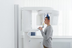 A young man has a computed tomography of the jaw, a circular snapshot of the jaw in modern dentistry. Prevention of caries, prosthetics and dental treatment. Radiology, panoramic scanner.