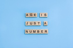 Phrase Age is Just a Number. Wooden blocks with letters on a light blue background. Ageism concept.