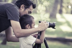 Dad is teaching photography to his son with vintage color tone
