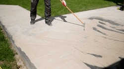 . Grouting paving slabs. Laying paving slabs. Pointing a patio with dry grouting cement grouting mix. Seeded fine sand on paving slabs - grouting.