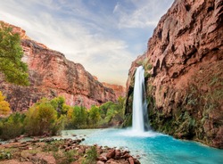 Beautiful turquoise waterfall coming out of red canyon wall