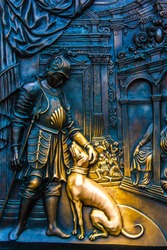 Close-up on one part of the bronze bas-relief with King Wenceslaus IV of Bohemia with his hunting dog on the pedestal of the statue of John of Nepomuk at the Charles Bridge in Prague, Czech Republic.