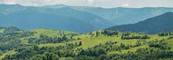 Blue mountains, green valley. Panoramic view of Ukrainian mountains in summer day. Carpathian, Ukraine, Europe. Mountain tourism. Tourism and travel concept. Natural green forest background panorama. 