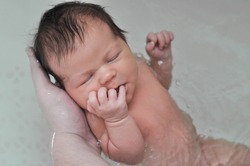 Childbirth in water - the first photo of the newborn baby. Father hahd holding a baby. Home birth, delivery
