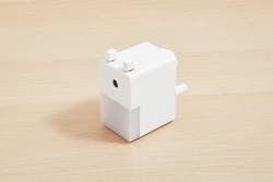 White rotary pencil sharpener isolated on wood background. Pencil sharpener. Minimalist design. Product design. Simplicity. Wood surface. Timber background. Stationery. Working table. 