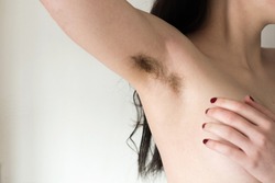 Beautiful female armpits with dark hair. Woman raising her arm and showing unshaven hairy armpits. Bodypositive, feminism and body care concept.