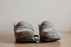 Two very worn, torn and widely used house slippers with a hole. Women's or girl's house slippers