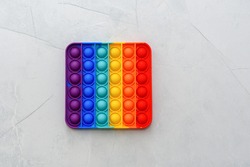 Rainbow Pop it fidget toy on a floor in home or school. Poppit -new fidget toy on empty grey copy space background.