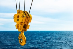 Crane hook in the sea with sky and clouds background on offshore platform.