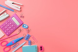 Stationary concept, Flat Lay top view Photo of Scissors, pencils, paper clips,calculator,sticky note,stapler and notepad in pink and blue tone on pink background with copy space.