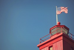 Red lighthouse with American flay flying