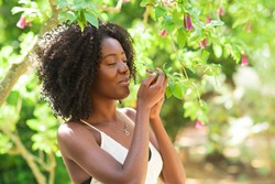 Content Black Woman Smelling Flowers in Park
