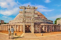 Tourist couple at Sanchi Stupa - a Buddhist stone structure located on a hilltop at Sanchi Town in Raisen District of the State of Madhya Pradesh, India