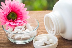 Selective Focus A Calcium white tablet a good supplement pills for woman bone in Healthy care Concept: decorated with pink flower 