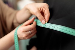 A centimeter is a tailor's tool for measuring when sewing. A centimeter is a tool for measuring dimensions. A meter for sewing clothes. Tailoring for the tailor. Human hands. Close up