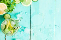 Refreshing summer drink - detox cocktail of mint, cucumber and lemon. On a light blue wooden table, bright sunlight, copy space, top view 