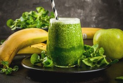 Organic vegetarian food. Fresh homemade raw vegetable and fruit green smoothie with apple, banana and lettuce leaves. On black plate with ingredients