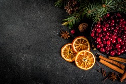 Ingredients for Christmas, winter baking cookies. Gingerbread, fruitcake, seasonal drinks. Cranberries, dried oranges, cinnamon, spices on a black stone table, copy space top view 