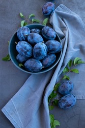 Fresh raw blue plums on the table, monochromatic color image