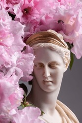 Still life of female divinity sculpture and flowering azalea flower
