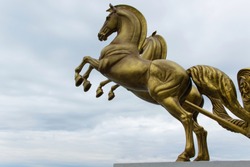 Bronze statue of two horses in motion with sky background and space for text