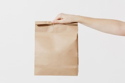 Close up female holds in hand brown clear empty blank craft paper bag for takeaway isolated on white background. Packaging template mock up. Delivery service concept. Copy space. Advertising area