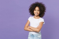 Smiling little african american kid girl 12-13 years old in white t-shirt isolated on pastel violet background studio portrait. Childhood lifestyle concept. Mock up copy space. Holding hands crossed
