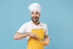 Excited young bearded male chef or cook baker man in apron white t-shirt toque chefs hat isolated on blue background in studio. Cooking food concept. Mock up copy space. Whipping beating eggs in bowl