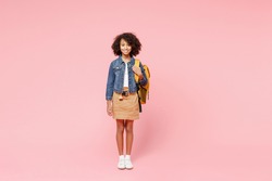Full length smiling little african american kid school girl 12-13 year old in casual denim clothes with backpack stand isolated on pastel pink background studio portrait. Childhood education concept.