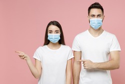 Young couple two friends man woman in white blank print design t-shirts sterile face mask to safe from coronavirus virus covid19 on quarantine posing isolated on pastel pink background studio portrait
