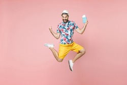 Full length happy traveler tourist man in summer clothes hat jumping hold passport tickets doing winner gesture isolated on pink background. Passenger traveling on weekend. Air flight journey concept