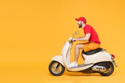 Delivery man in red cap t-shirt uniform driving moped motorbike scooter isolated on yellow background studio Guy employee working courier Service quarantine pandemic coronavirus virus covid19 concept