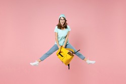 Full length portrait of excited young woman student in t-shirt hat glasses hold backpack jumping spreading legs isolated on pink background studio. Education in high school university college concept