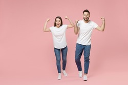 Full body length young cheerful fun couple two friends bearded man brunette woman in white basic blank print design t-shirts jeans celebrating isolated on pastel pink color background studio portrait