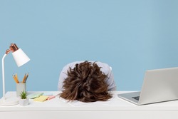 Young tired exhausted frustrated secretary employee business woman wearing casual shirt sit work sleep laid her head down on white office desk with pc laptop isolated on pastel blue background studio