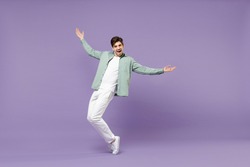 Full lengthoverjoyed caucasian man in casual mint shirt white t-shirt standing on toes dancing leaning back fooling around isolated on purple color background studio portrait People lifestyle concept