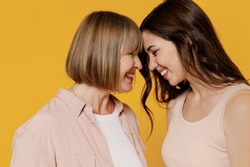 Side view two young tender happy lovely smiling daughter mother together couple women in casual clothes hug touch forehead isolated on plain yellow background studio portrait Family lifestyle concept.