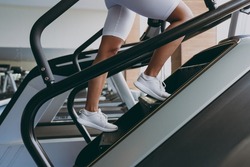 Cropped up photo shot young strong skinny sporty athletic sportswoman woman in white sportswear warm up train run on a treadmill climber stairs machine in gym indoor Workout sport motivation concept
