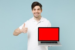 Young fun man in white casual basic t-shirt hold laptop pc computer with blank screen workspace area show thumb up gesture isolated on pastel blue background studio portrait People lifestyle concept
