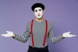 Confused perplexed concerned preoccupied young mime man with white face mask wears striped shirt beret looking camera spreading hands isolated on plain pastel light violet background studio portrait