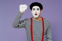 Surprised confused preoccupied perplexed puzzled young mime man with white face mask wears striped shirt beret making knocking gesture isolated on plain pastel light violet background studio portrait
